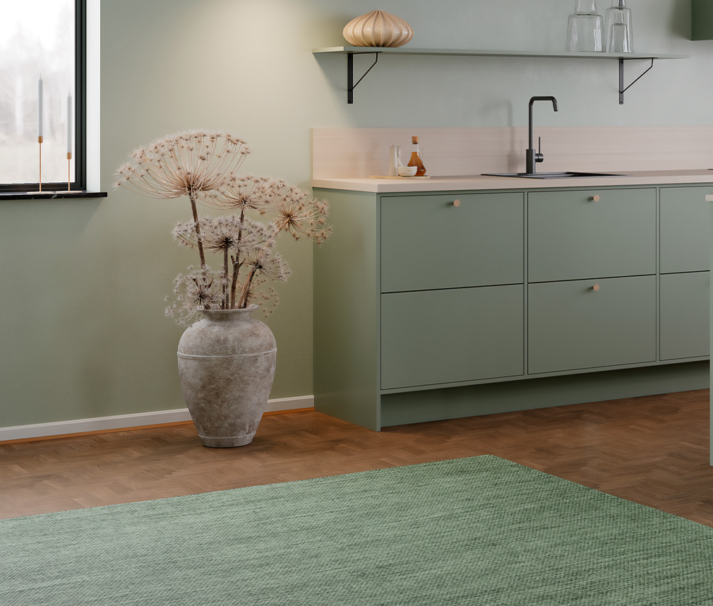 Modernt och stilrent kök i grön färg med svart diskho och blandare