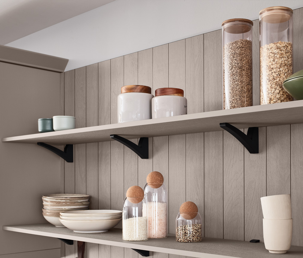 Öppna hyllor i ett shaker kök i beige färg med svarta detaljer